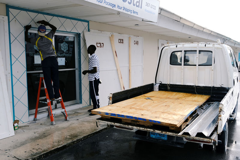 © Reuters. Workers install storm shutters before the arrival of Hurricane Dorian in Marsh Harbour