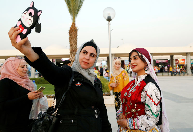© Reuters. A woman takes a selfie with a mobile phone outside the annual Damascus International Trade Fair