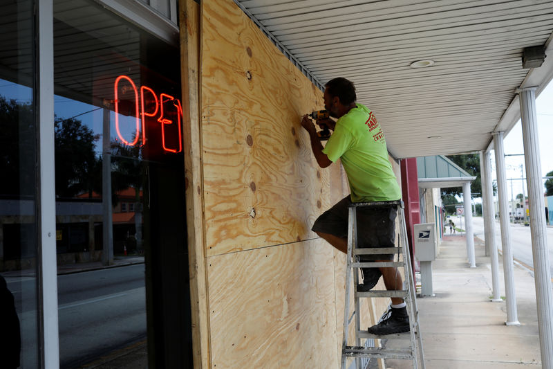 © Reuters. Un hombre tapa las ventanas de un negocio antes de la llegada del huracán Dorian en Florida