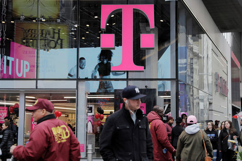 © Reuters. FILE PHOTO: Pedestrians walk past a T-Mobile store in New York