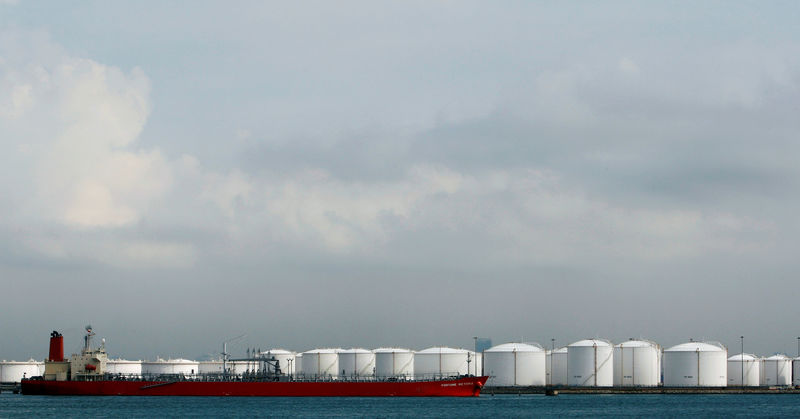 © Reuters. FILE PHOTO: Ship is moored near storage tanks at oil refinery off coast of Singapore