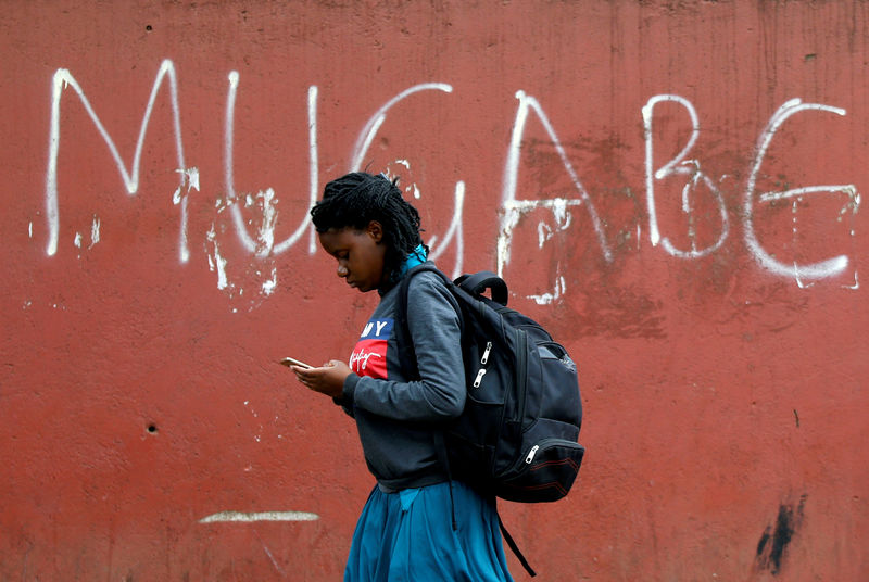 © Reuters. FILE PHOTO: A woman walks past a wall with "Mugabe" written on it, in Mbare township, Harare