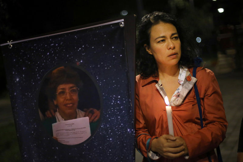 © Reuters. Neighbor of Cristina Vazquez holds a candle during a vigil to commemorate her death in Mexico City