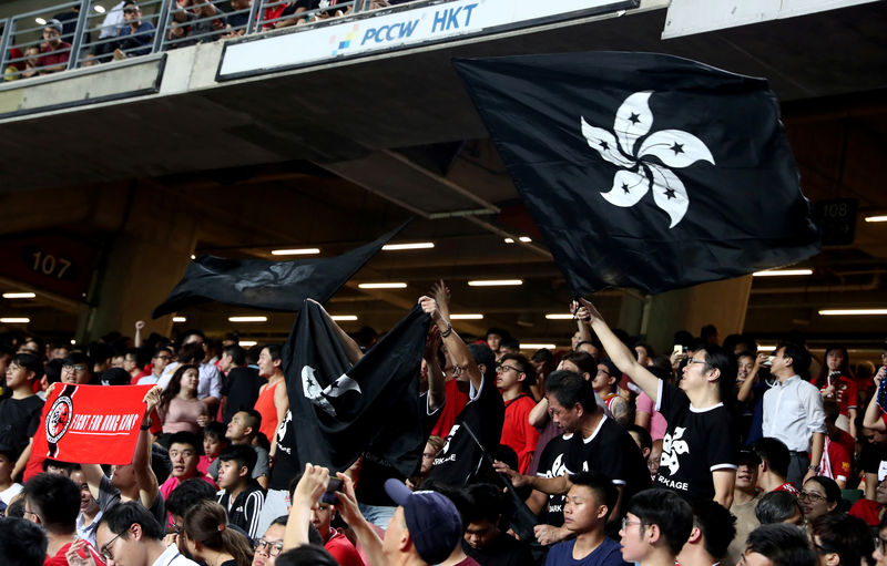 © Reuters. Los manifestantes agitan banderas negras de Hong Kong en apoyo de los manifestantes antigubernamentales en un partido de clasificación para la Copa Mundial de fútbol entre Hong Kong e Irán, en el estadio de Hong Kong