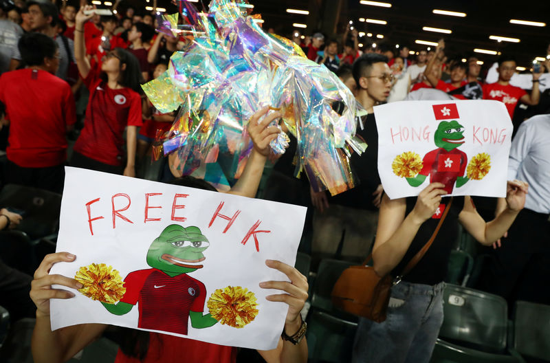 © Reuters. Soccer fans hold placards in support of anti-government protesters during a football World Cup qualifier match between Hong Kong and Iran, at Hong Kong Stadium