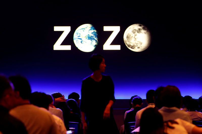 © Reuters. FILE PHOTO: A woman is seen in front of a sign reading Zozo, which operates Japan's popular fashion shopping site Zozotown, at an event in Tokyo launching the debut of its formal apparel items
