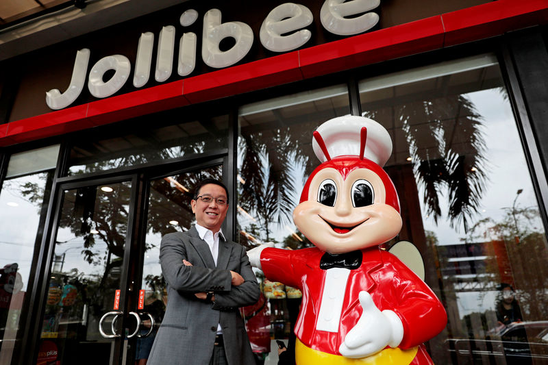 © Reuters. Ernesto Tanmantiong, the president and CEO of Philippine national champion Jollibee Foods Corp., poses for a picture beside a Jollibee mascot outside a Jollibee branch in Pasig City