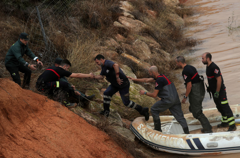 © Reuters. Rescue workers help a man who was stranded inside a flooded tunnel after heavy floods in Pilar de la Horadada