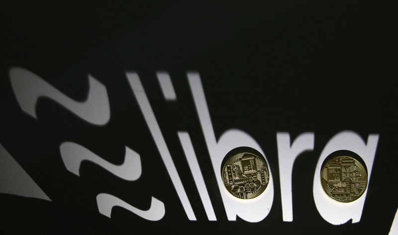 © Reuters. Shadow of a 3D-printed Facebook Libra cryptocurrency logo is seen near cryptocurrency representation in this illustration taken