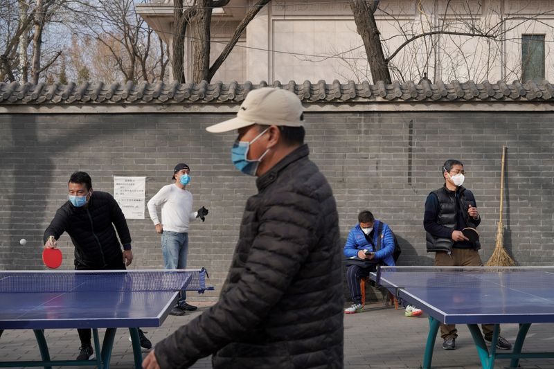 © Reuters. People wearing face masks play table tennis at a park, following an outbreak of the novel coronavirus in the country, in Beijing
