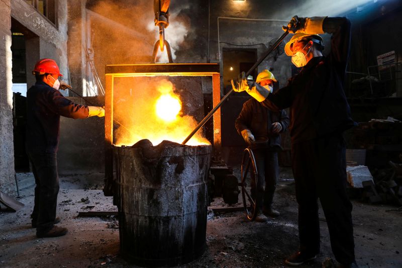 © Reuters. Trabajadores con máscaras faciales trabajan junto a un horno en una planta siderúrgica en Hangzhou, Zhejiang