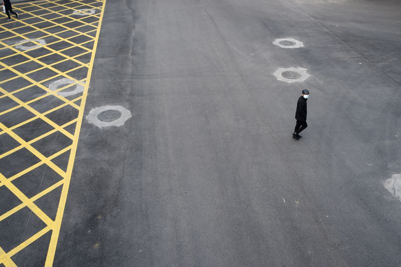 © Reuters. Man wearing a face mask crosses a road in Wuhan, the epicentre of the novel coronavirus outbreak