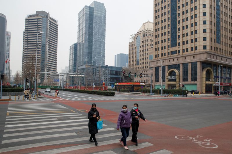 © Reuters. Personas usan máscaras de protección mientras cruzan una calle en el Distrito Comercial Central de Pekín, en momentos en que China se ve afectada por un brote del nuevo coronavirus, en Pekín