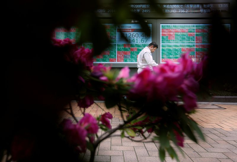 © Reuters. A passerby walks past in front of a stock quotation board outside a brokerage in Tokyo