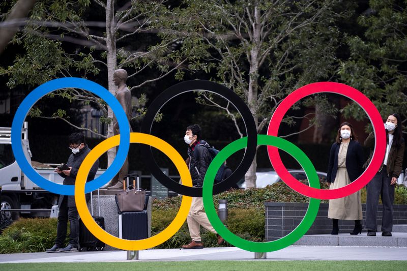 © Reuters. People wearing protective face masks, following an outbreak of the coronavirus, are seen next to the Olympic rings in front of the Japan Olympic Museum in Tokyo