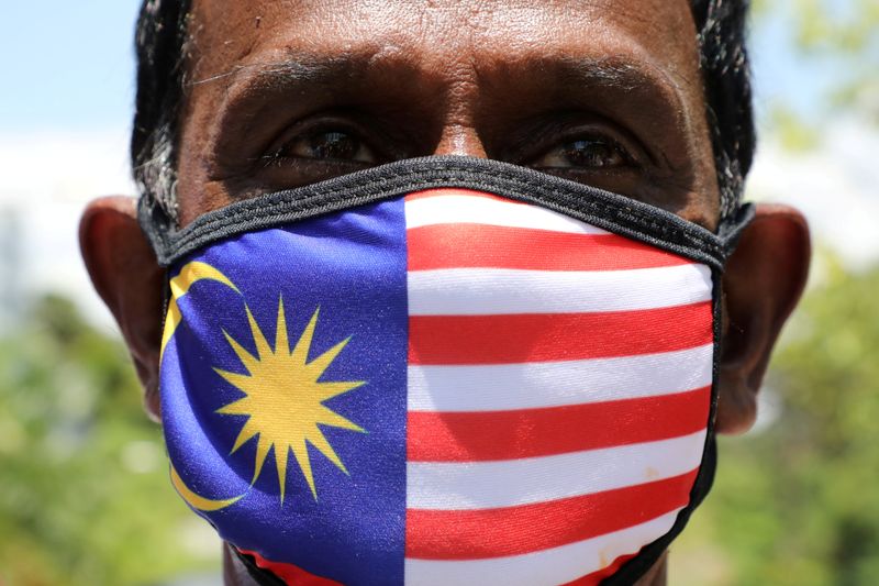 © Reuters. A supporter of People's Justice Party wearing Malaysia's flag mask pose for a picture outside National Palace, Kuala Lumpur