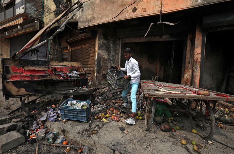 © Reuters. A shopkeeper salvages his belongings from his damaged shop that was set on fire by a mob in a riot affected area after clashes erupted between people demonstrating for and against a new citizenship law in New Delhi