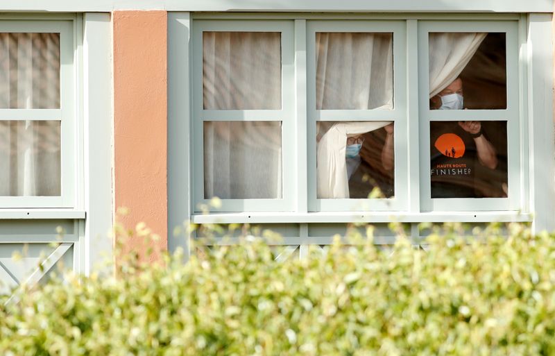 © Reuters. Huéspedes con mascarillas miran por la ventana de una habitación del hotel H10 Costa Adeje Palace en Tenerife