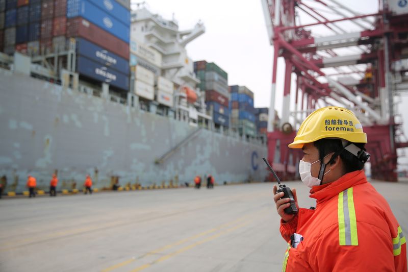 © Reuters. Foreman wearing a face mask works as a cargo ship docks at a container terminal of Qingdao port