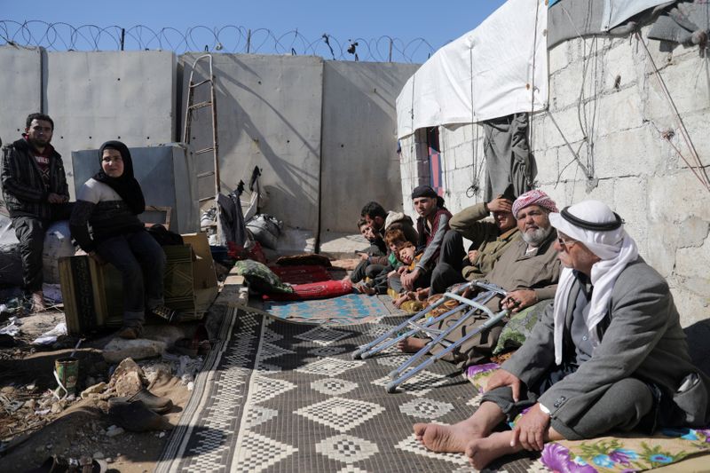 © Reuters. FOTO DE ARCHIVO: Una familia siria internamente desplazada se sienta cerca una tienda de campaña cerca del muro en el campamento de Atmah, situado cerca de la frontera con Turquía, Siria, el 26 de febrero de 2020