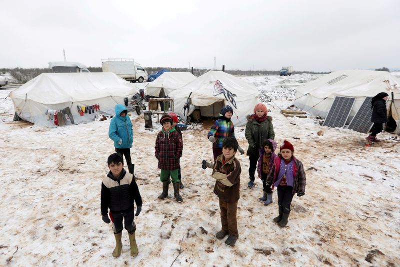 © Reuters. FILE PHOTO: Internally displaced children stand on snow near tents at a makeshift camp in Azaz