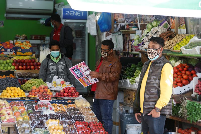 © Reuters. Foto del jueves de vendedores con máscaras en una verdulería en Manamá, Bahréin