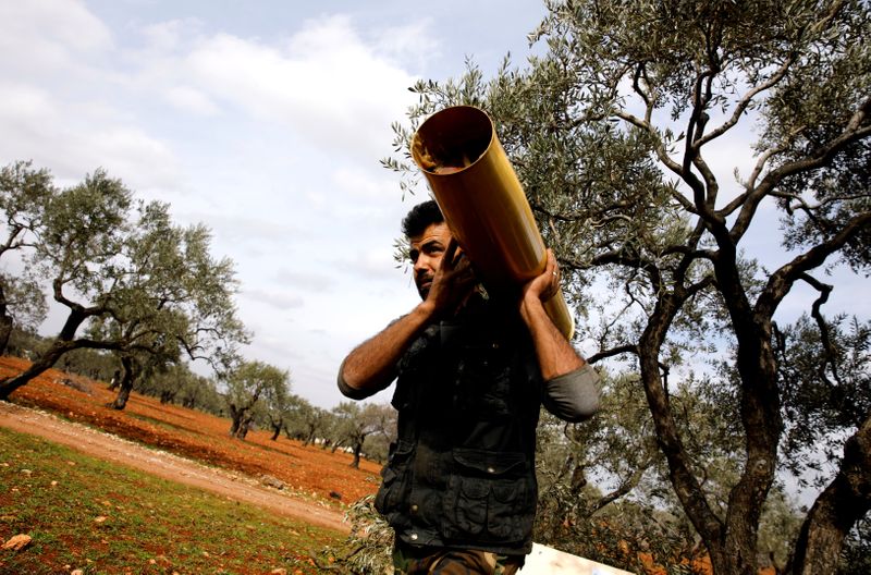 © Reuters. A Syrian fighter carries a shell case to an artillery near Idlib