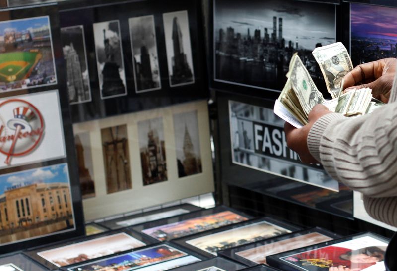 © Reuters. FILE PHOTO: A vendor counts money at his photograph stand at Times Square in New York