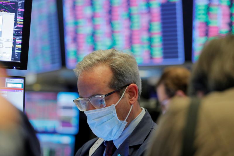 © Reuters. FILE PHOTO: A trader wears a mask as he works on the floor of the New York Stock Exchange (NYSE) as the building prepares to close indefinitely due to the coronavirus disease (COVID-19) outbreak in New York
