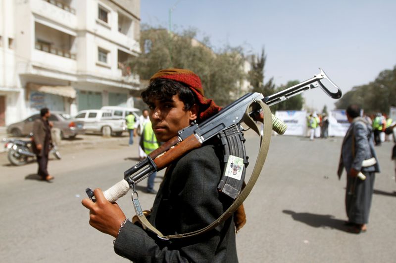 © Reuters. FILE PHOTO: A Houthi supporter looks on as he carries a weapon during a gathering in Sanaa