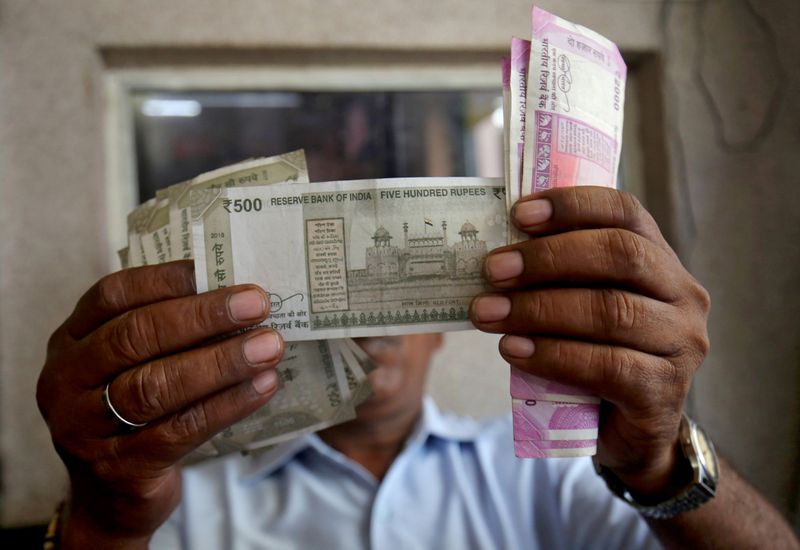 © Reuters. FOTO DE ARCHIVO: Un cajero revisa las notas de rupias indias dentro de una habitación en una estación de combustible en Ahmedabad