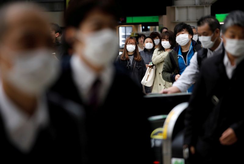 &copy; Reuters. Alcuni passeggeri indossano maschere protettive in una stazione di Tokyo