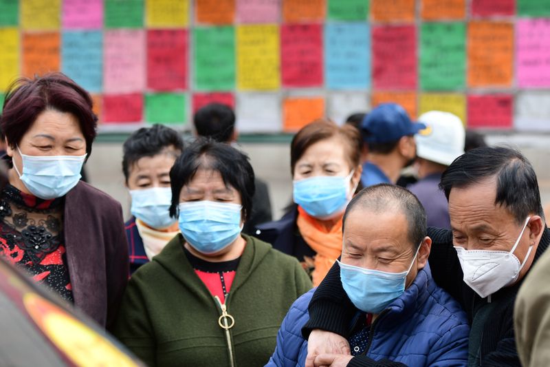 &copy; Reuters. Personas usando mascarillas para prevenir la propagación del coronavirus (COVID-19) miran los anuncios de trabajo en Qingdao