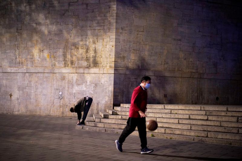 &copy; Reuters. FILE PHOTO: People wearing face masks exercise on a street in Wuhan