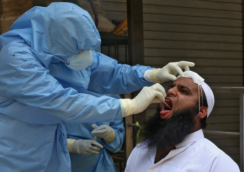 &copy; Reuters. Médico com roupa de proteção colhe amostra de homem para teste de coronavírus em Mumbai, na Índia