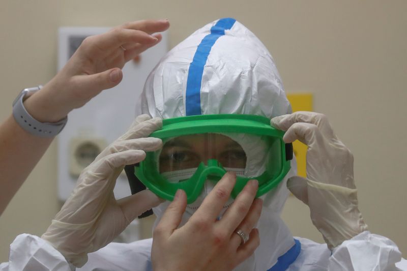 © Reuters. FILE PHOTO: A medical specialist puts on protective gear during a demonstration prior to the opening of a new section for treatment of patients affected by the coronavirus disease at a hospital in Moscow