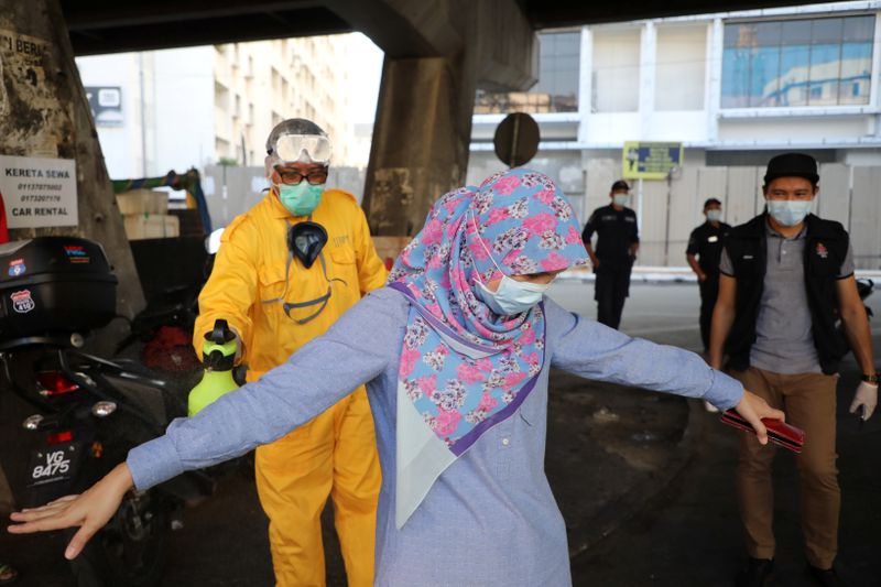&copy; Reuters. FILE PHOTO:  A worker sprays disinfectant on a woman during the movement control order due to the outbreak of the coronavirus disease (COVID-19), in Kuala Lumpur