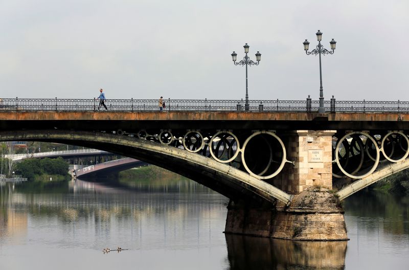 &copy; Reuters. La gente camina por el puente de Triana durante el brote de la enfermedad coronavirus (COVID-19), en la capital andaluza de Sevilla, España