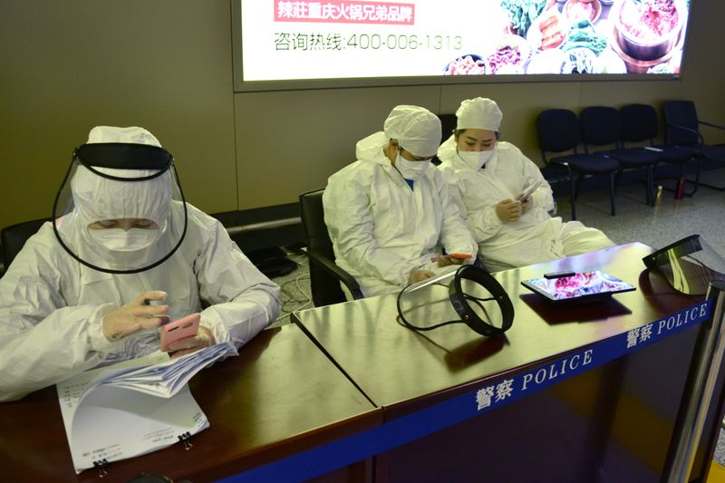 © Reuters. Workers in protective suits are seen at a registration point for passengers at an airport in Harbin, capital of Heilongjiang province bordering Russia, following the spread of the novel coronavirus disease (COVID-19) continues in the country