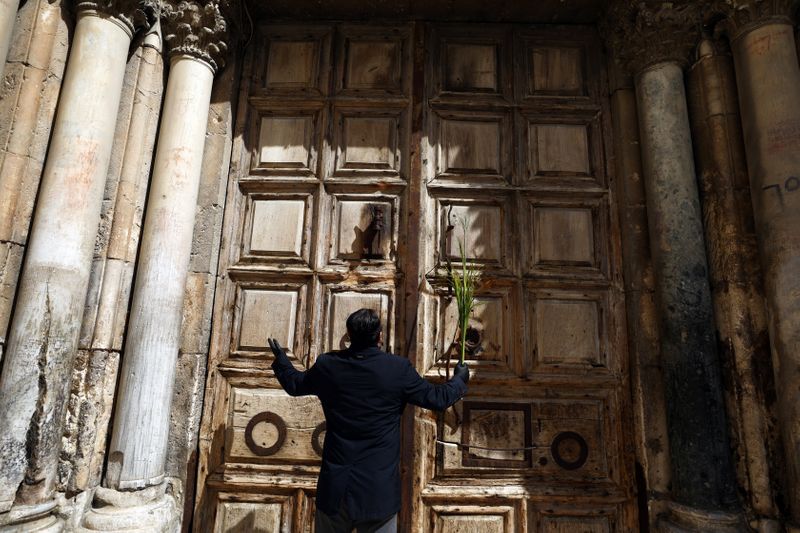 &copy; Reuters. An Orthodox Christian worshipper holds a palm frond outside the closed doors of the Church of the Holy Sepulchre on Orthodox Palm Sunday amid the coronavirus disease (COVID-19) outbreak, in Jerusalem&apos;s Old City