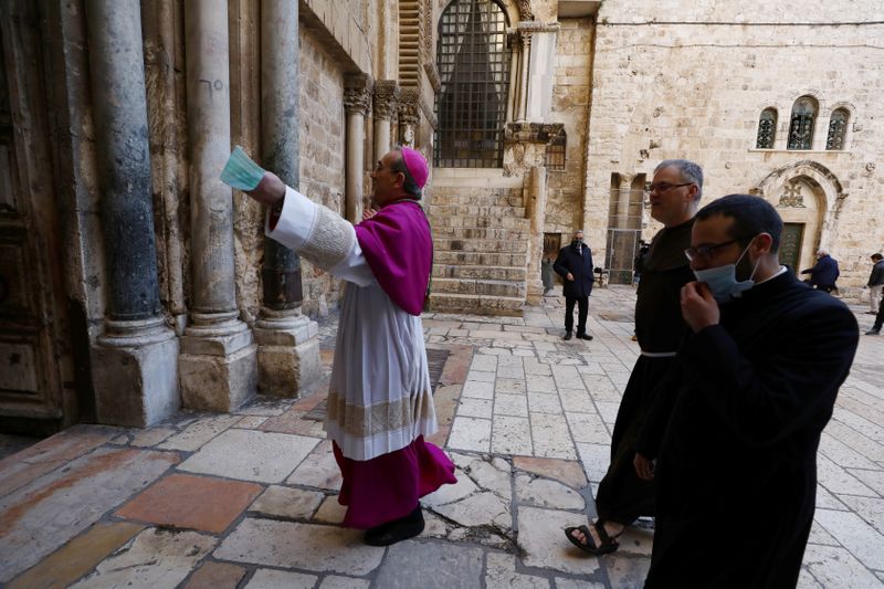 © Reuters. Archbishop Pierbattista Pizzaballa, holds a masks as he enters the Church of the Holy Sepulchre before the start of the Easter Sunday service amid the coronavirus disease (COVID-19) outbreak, in Jerusalem's Old City