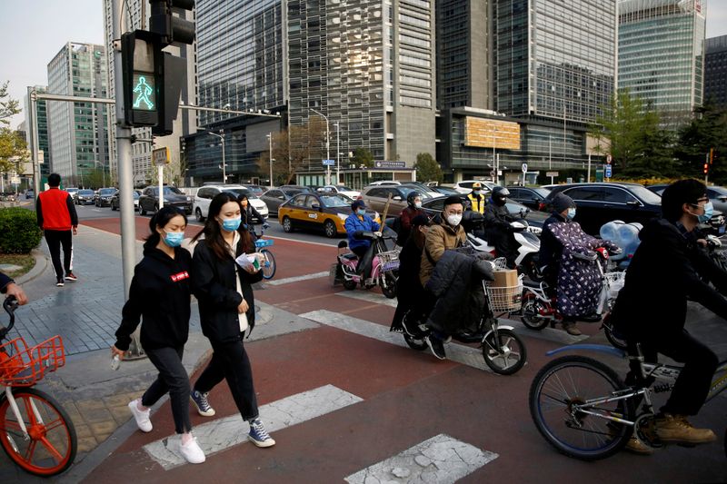 © Reuters. Las personas que usan máscaras faciales cruzan una calle en la calle financiera de Beijing durante la hora pico de la tarde, cuando el país se ve afectado por un brote de la nueva enfermedad por coronavirus (COVID-19)