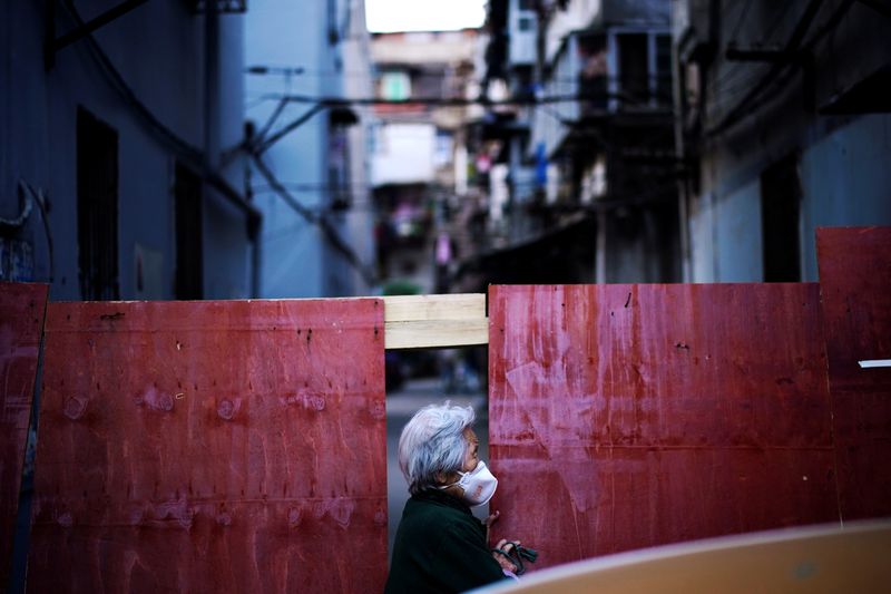 © Reuters. A resident wearing a face mask is seen at a blocked residential area after the lockdown was lifted in Wuhan