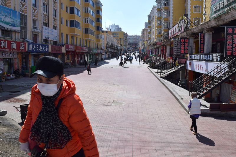 &copy; Reuters. Resident wearing a face mask walks past a shopping street which used to be packed with people in Suifenhe, a city of Heilongjiang province on the border with Russia, as the spread of the novel coronavirus disease (COVID-19) continues in the country