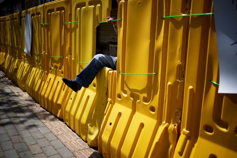 &copy; Reuters. Homem atravessa buraco em barreira de proteção construída em Wuhan, na China