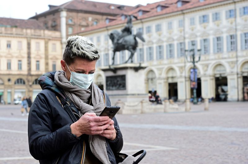 &copy; Reuters. FILE PHOTO: Woman wearing a protective mask uses her mobile phone, as a coronavirus outbreak continues to grow in northern Italy, in Turin