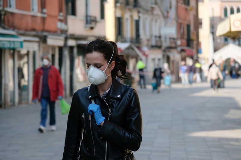 © Reuters. Люди в медицинских масках и перчатках в Венеции