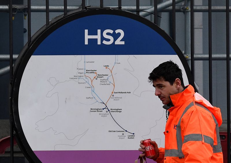 &copy; Reuters. FILE PHOTO: An HS2 worker walks past signage on perimeter fencing at the HS2 high speed rail link construction site in Euston, London