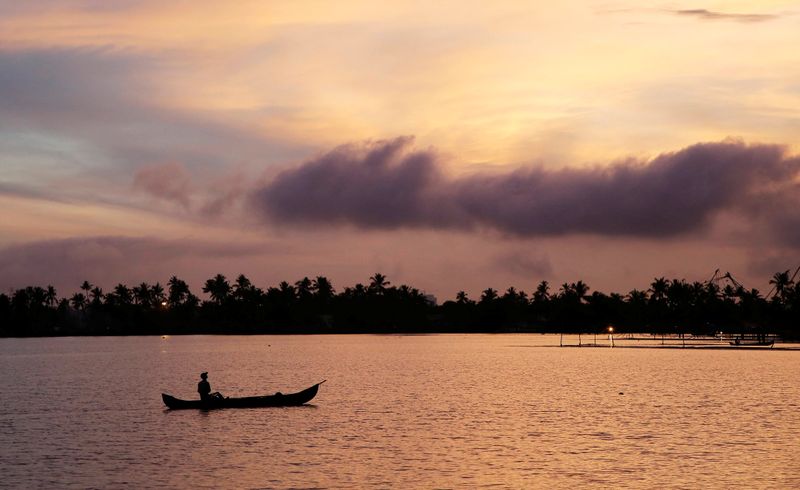 &copy; Reuters. A man rows his boat in the tributary waters of Vembanad Lake against the backdrop of pre-monsoon clouds on the outskirts of Kochi