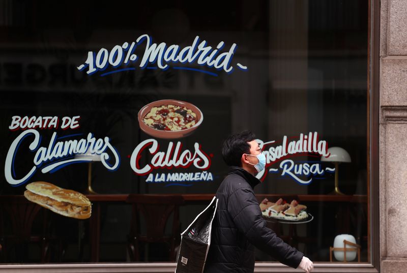 &copy; Reuters. Un hombre con una máscara protectora pasa por delante de un restaurante cerrado en medio del brote de la enfermedad coronavirus (COVID-19) en Madrid, España